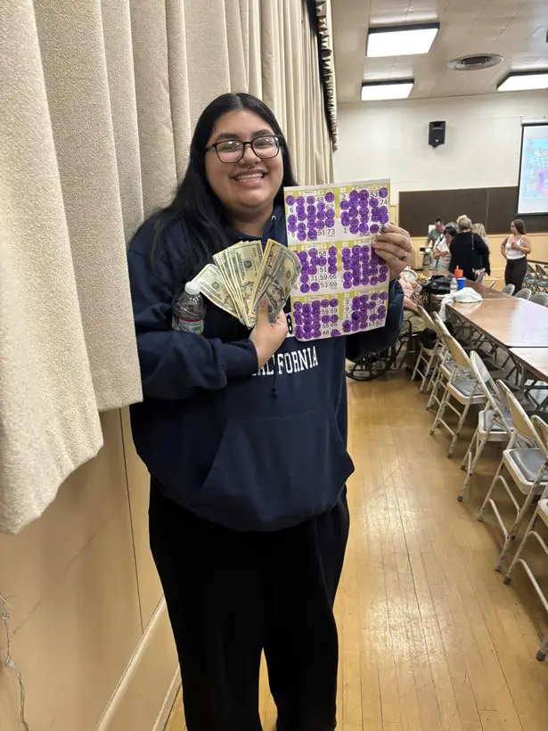 A Wine Country Bingo player smiling with her marked card and cash prize.
