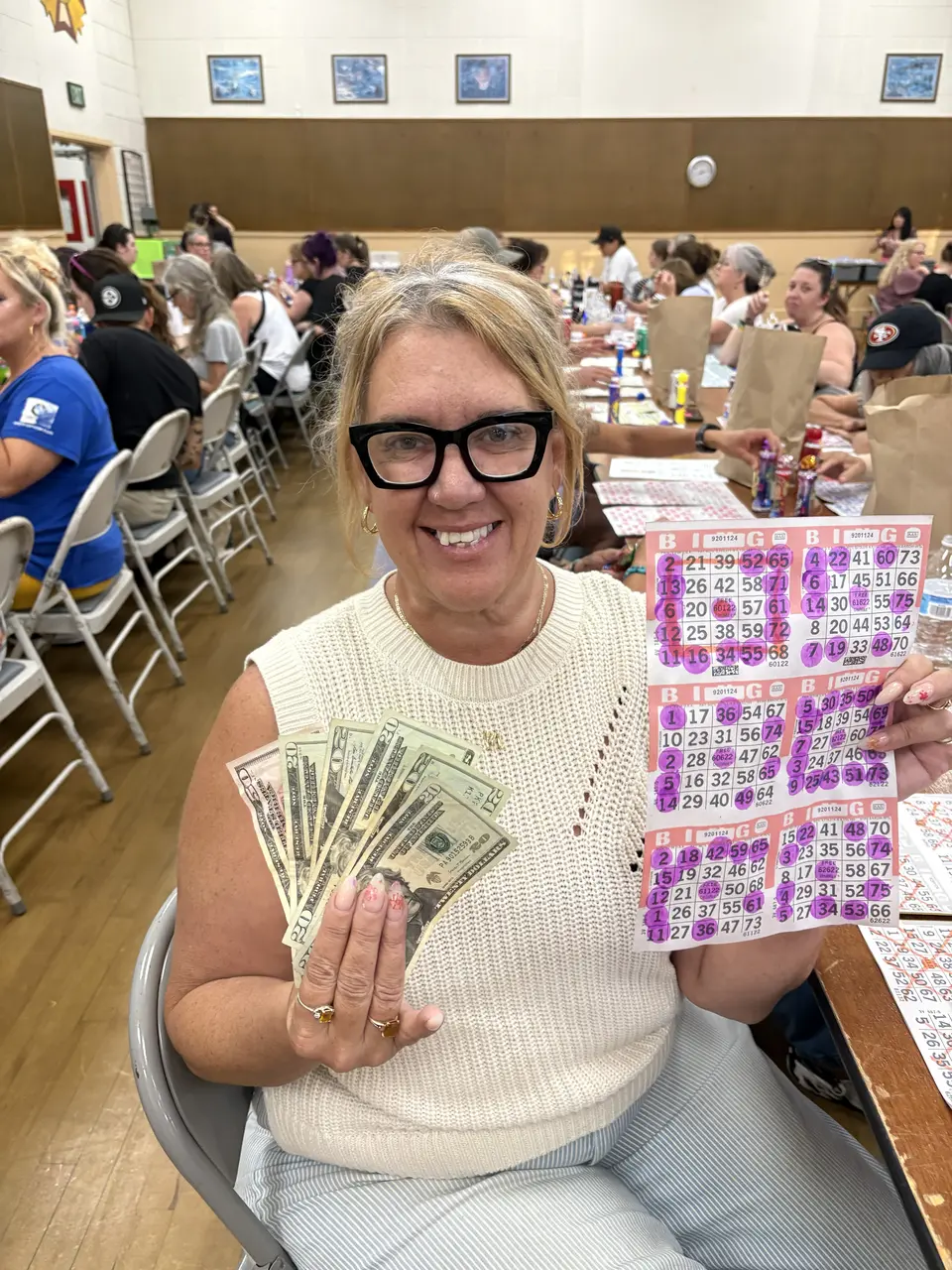 A Wine Country Bingo winner holding her marked card and cash prize.