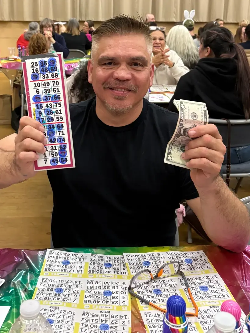 A Wine Country Bingo winner holding his winning card and cash.